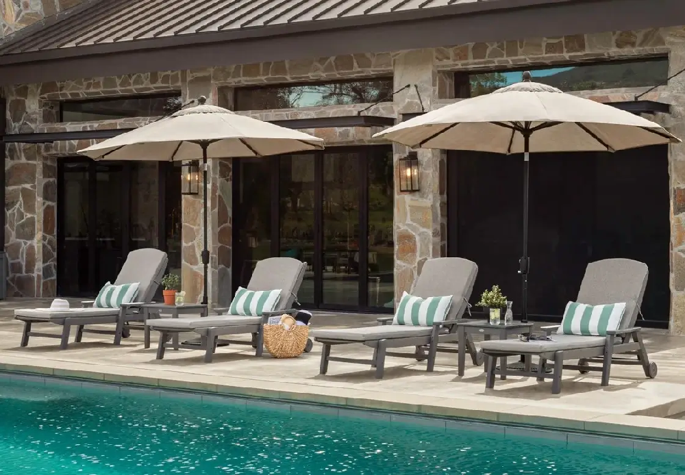 Luxury pool deck featuring cushioned commercial  Nautical chaise lounges and large market umbrellas creating a relaxing resort-style retreat.